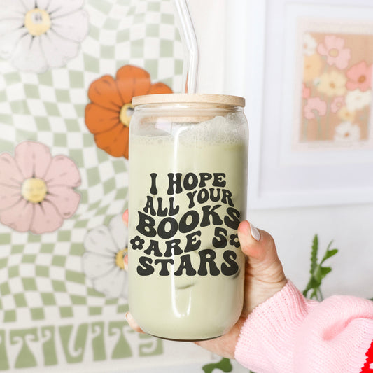 A frosted glass cup with a bamboo lid and glass straw featuring a bold, retro-style design that reads "I Hope All Your Books Are 5 Stars." Held against a colorful floral and checkered background, this aesthetic bookish drinkware is perfect for readers who love rating books and enjoying their favorite iced coffee, tea, or matcha in style. A must-have for book lovers who adore fun, literary-themed accessories.
